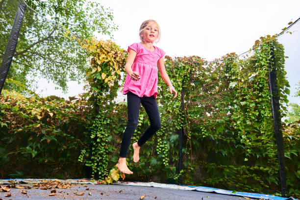 istock Child cute blond girl playing and jumping on trampoline 1053561762