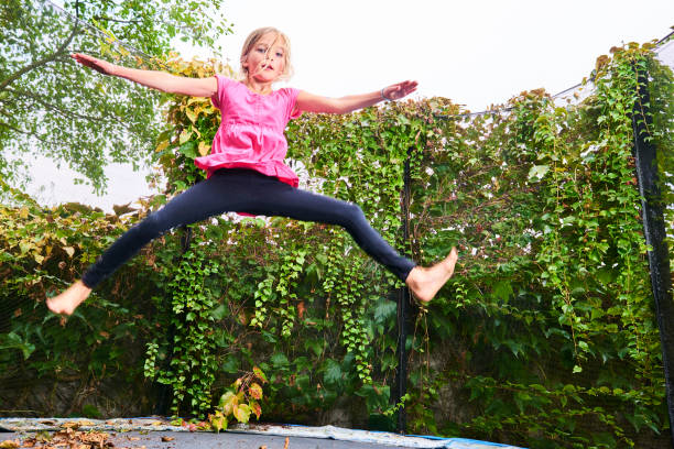 istock Child cute blond girl playing and jumping on trampoline 1053562006