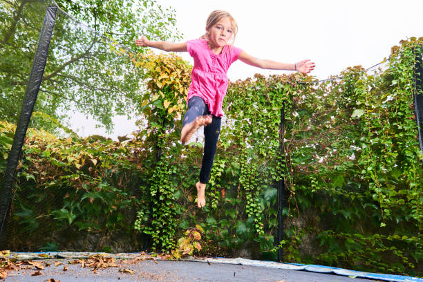 istock Child cute blond girl playing and jumping on trampoline 1053562016