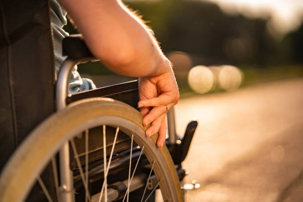 Close up women hand holding wheel on a wheelchair during sunset