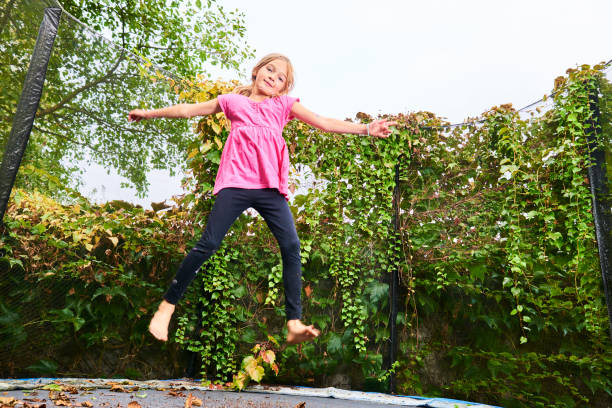 istock Child cute blond girl playing and jumping on trampoline 1053563470