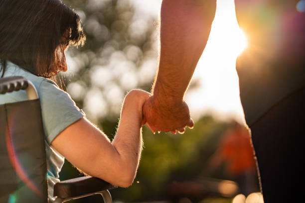 Couple hands during sunset Close up women on a wheel chair holding mens hand respect stock pictures, royalty-free photos & images