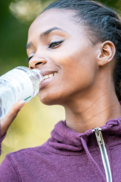 istock Smiling beautiful young black woman drinking bottled water 1053564788