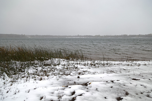 Cold and hazy lake during a early winter snowfall.