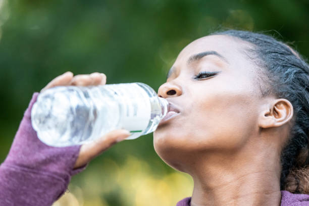 istock Smiling beautiful young black woman drinking bottled water 1053566182