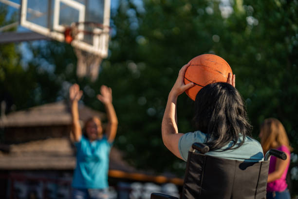 mädchen basketball spielen mit frauen auf einen rollstuhl - basketball teenager nature outdoors stock-fotos und bilder