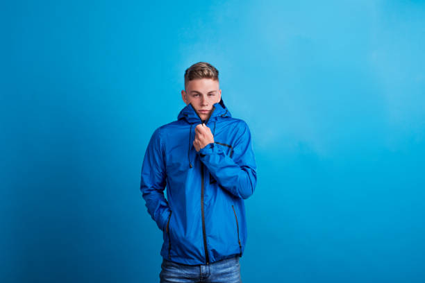 istock Portrait of a young man with blue anorak in a studio, feeling cold. 1053574656