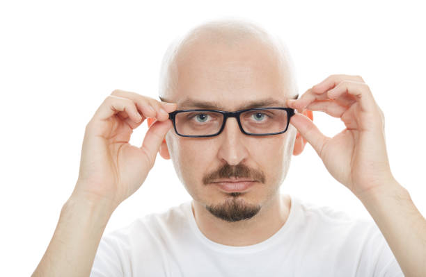 Bald young man with eyeglasses looking at camera on white background