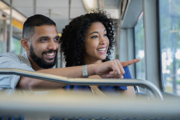 pareja de jóvenes turistas mirando por la ventana del tren de cercanías en la ciudad de - couple young adult african descent multi ethnic group fotografías e imágenes de stock