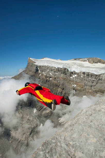 istock Wingsuit flier launches from cliff, in mountains 1053590622
