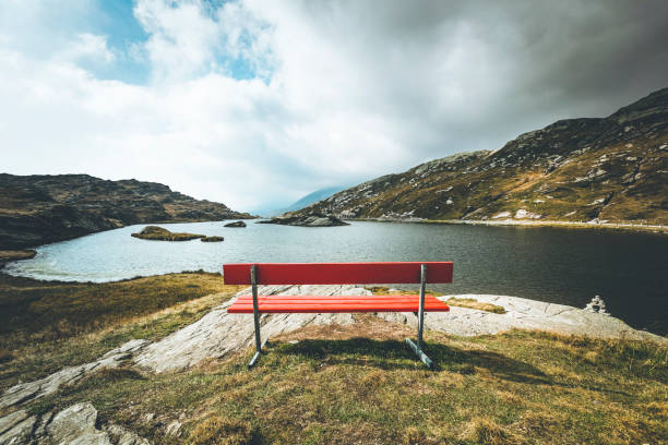 red bench with a view, mountain lake san bernardino, switzerland red bench at 2066m above sea level at the san bernardino pass in switzerland, europe. lepontine alps stock pictures, royalty-free photos & images