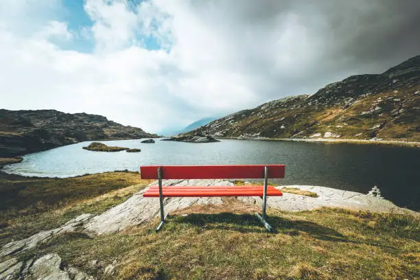 Photo of red bench with a view, mountain lake san bernardino, switzerland