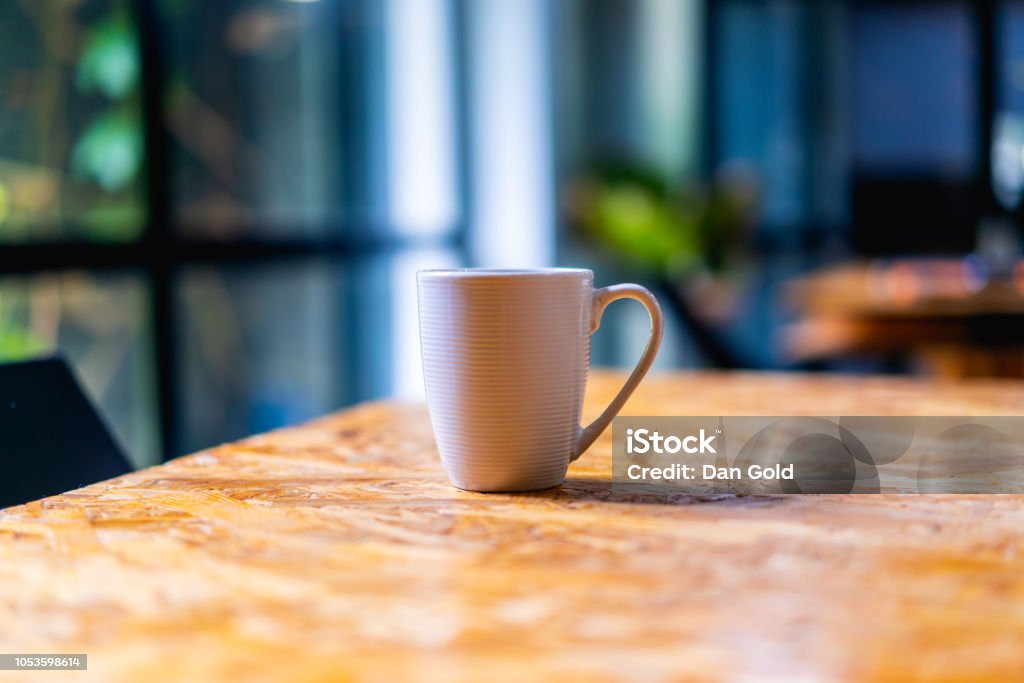 Blanco taza de café o té en una textura escritorio cerca de una ventana en una oficina o espacio de coworking - Foto de stock de 2015 libre de derechos