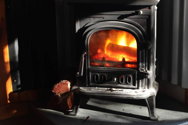 istock A black cast iron fire place with wood burning inside of it. Keeping warm concept image. 1053601754