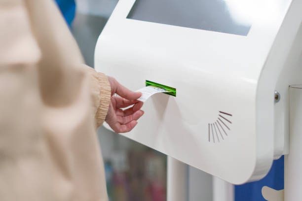 cerca mano tire al cliente un número de ticket de máquina dispensador a esperar en cola en la oficina de correos f - hospital entrada fotografías e imágenes de stock