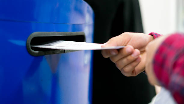close up hand drop letter and documents in the blue postbox in post office mail f