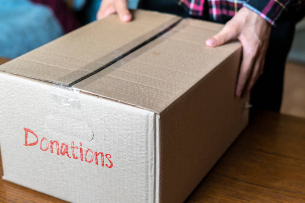hands bringing the box with dontations for poor people on a wooden table concept