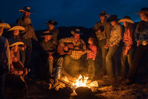 duża grupa kowbojów śpiewających i grających na gitarze przy ognisku - cowboy cowboy hat hat summer zdjęcia i obrazy z banku zdjęć