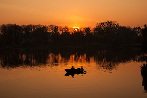 Young couple in a boat sailing on a lake at sunset.