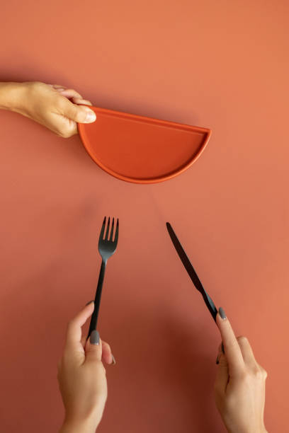 istock Women hands holding ceramic tableware at orange background 1053610222