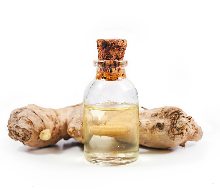 Ginger root and ginger oil in a glass bottle isolated on a white background