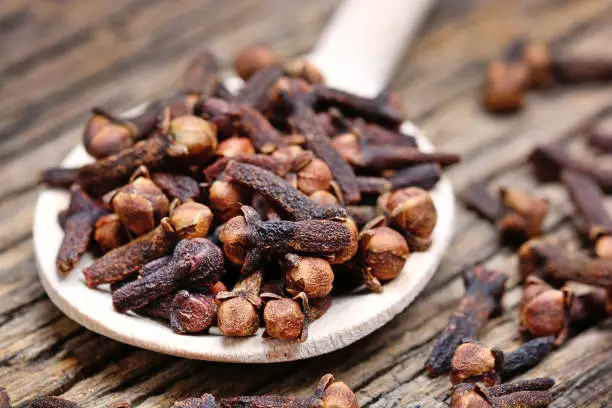 Close up of clove in a wooden spoon on old table