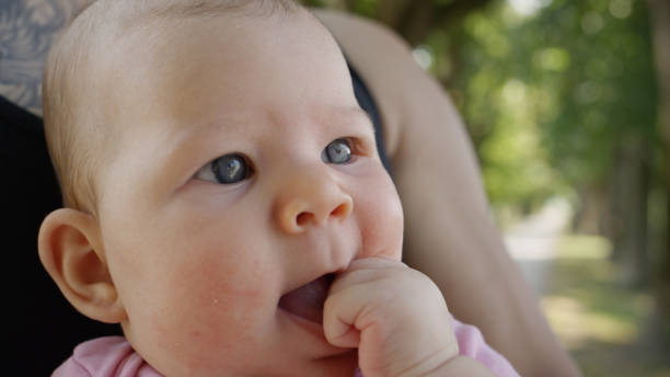 istock CLOSE UP: Cute baby girl puts her tiny hand in her mouth while in dad's lap. 1053639868