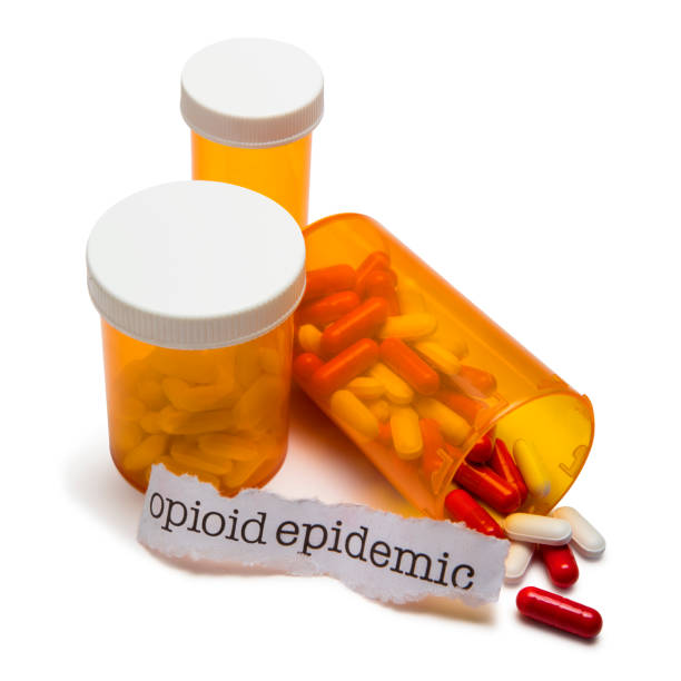 Opioid Epidemic This it is a photograph of orange prescription bottles with opioids pouring out. There is a typewriter written text on a torn piece of paper spelling out opioid epidemic as a symbol of the crisis that is happening in America. epidemic stock pictures, royalty-free photos & images