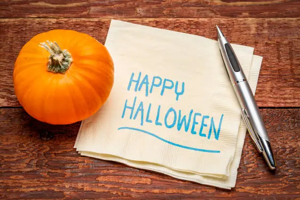Happy Halloween greetings - handwriting on a napkin with a pumpkin gourd against rustic barn wood