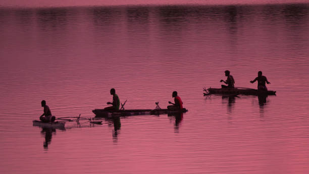 sylwetka nierozpoznawalni miejscowi rybacy łowiący małe łodzie o różowym wschodzie słońca - fishing nautical vessel small men zdjęcia i obrazy z banku zdjęć
