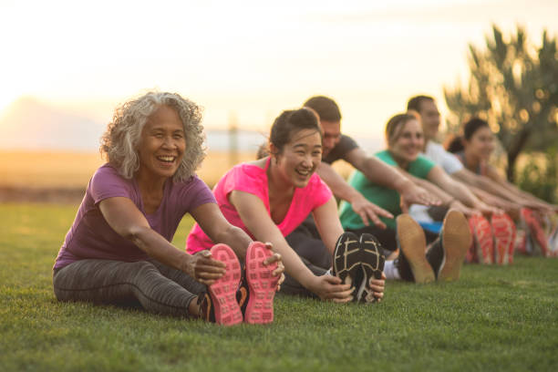 istock Group doing co-ed yoga outside in the morning 1053669890