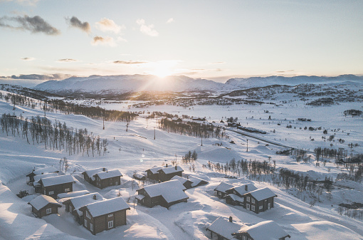 View of sunset over huts in Norwegian winter landscape.