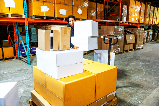 Young male warehouse worker loading boxes in a warehouse