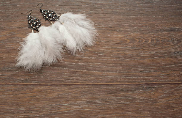 istock Beautiful delicate earrings with feathers on a wooden background. 1053705754