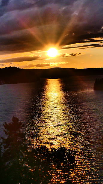 istock Sunset with bright halo on water and deciduous trees 1053712342