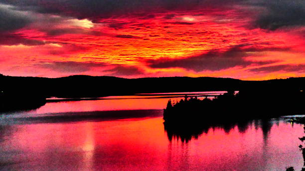 istock Bright pink sunset over tree-lined water with an island 1053712426
