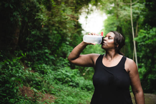 donna positiva al corpo idratante durante il bottaio - african descent healthy lifestyle people water foto e immagini stock