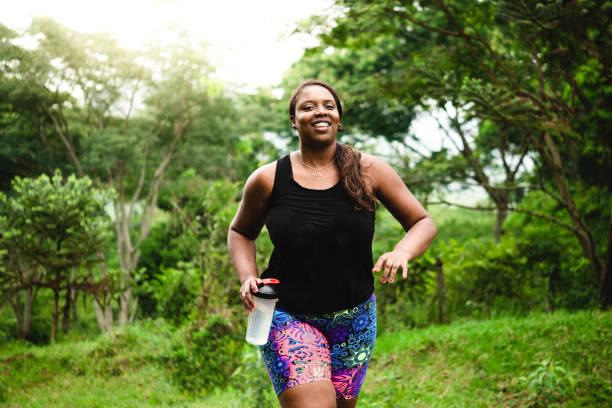 mulher positiva de corpo exercitando na natureza - running jogging african descent nature - fotografias e filmes do acervo