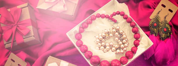 Opened gift box with necklace over pink background with copy space, overhead view