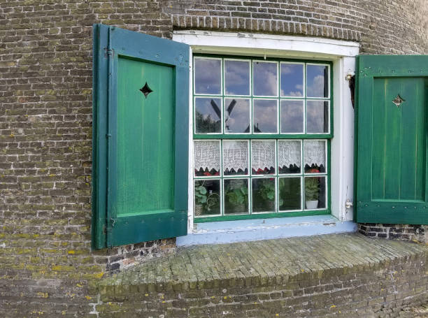 istock windmill window with green shutters and brick wall 1053716108