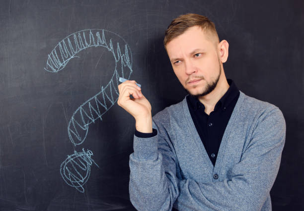 istock a bearded man thinks near a black school board with question mark on it 1053718394