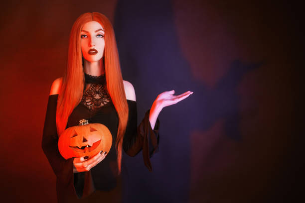 Dark halloween costume. Spooky witch with red lips in darkness. Gothic woman vampire in black dress holding pumpkin jack. Gothic look. Scary halloween pumpkin jack lantern. Spooky darkness Dark halloween costume. Spooky witch with red lips in darkness. Gothic woman vampire in black dress holding pumpkin jack. Gothic look. Scary halloween pumpkin jack lantern. Spooky darkness vampire woman stock pictures, royalty-free photos & images