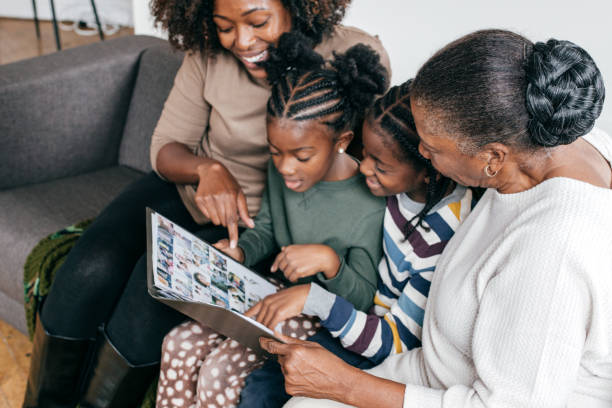 abuela, hija y nietos mirando el álbum de fotos - hablar fotos fotografías e imágenes de stock