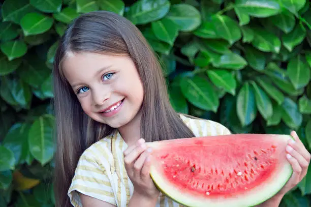 A portrait of a pretty girl ready to enjoy a juicey watermelon outside in the summer.