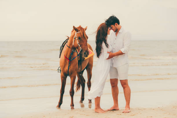 istock Young couple goes horse riding on tropical beach. 1053748852