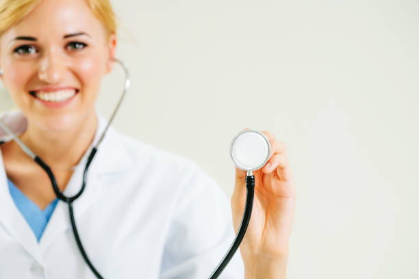 Young female doctor pointing stethoscope at blank space. Selective focus at doctors hand. Medical healthcare concept.