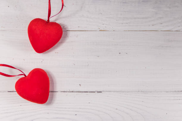 istock Two red hearts on white wooden background 1053753422