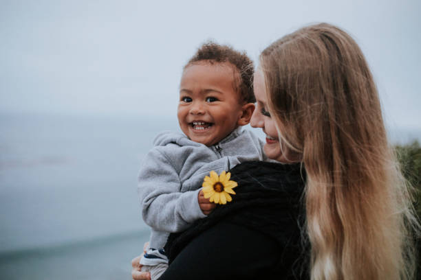 jungen, die eine blume getragen von seiner mutter - baby toddler child flower stock-fotos und bilder