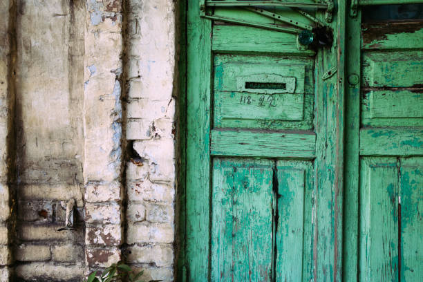 istock Old cracked green door with handle. Painted brick wall 1053758734