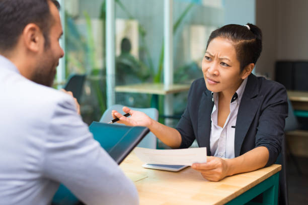 istock Displeased Asian female boss looking at Latin subordinate 1053760440